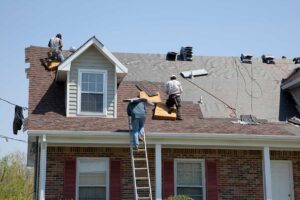 A roofer installing new asphalt shingles on a suburban home roof during daylight.