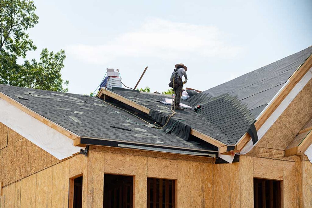 A homeowner reviews loan documents and estimates while a roofing project is underway on a single-family house.