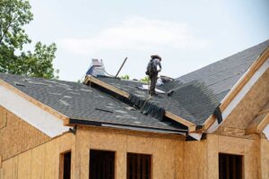 A homeowner reviews loan documents and estimates while a roofing project is underway on a single-family house.