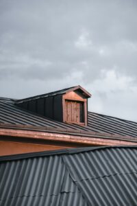 Residential roof with slate, metal, and asphalt roofing samples beside tools and winter-weather inspection notes.